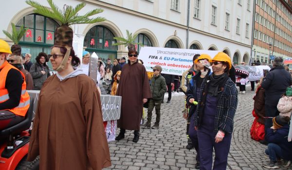 Menschen sind als Bauarbeiter und andere als Palmen verkleidet.