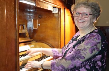 Eine Frau sitzt vor einer Orgel und spielt darauf.