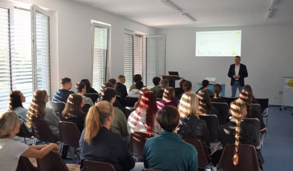 Jugendliche sitzten in Stuhlreihen nebeneinander. Vor ihnen steht der Bürgermeister.