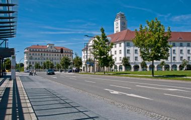 In der Mitte steht ein weißes Gebäude mit einem Turm. Es ist das Rathaus der Stadt Sonneberg. Auf der linken Seite steht ein weiteres Gebäude. Die Sonne scheint.