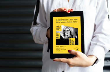 Person hält Tablet mit Veranstaltungshinweis in der Hand