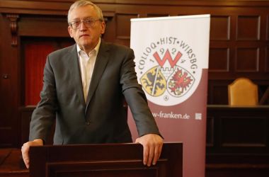 Ein Mann steht an einem Rednerpult. Es ist Professor Dippold.