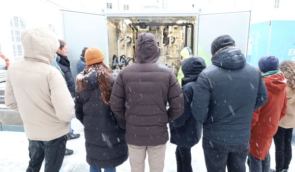 Interessierte Gäste schauen sich eine technische Anlage in einem Container an.