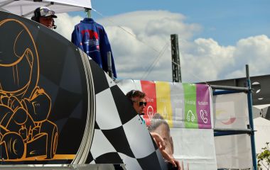 Zwei Kommentatoren mit Headsets stehen an der Startlinie.