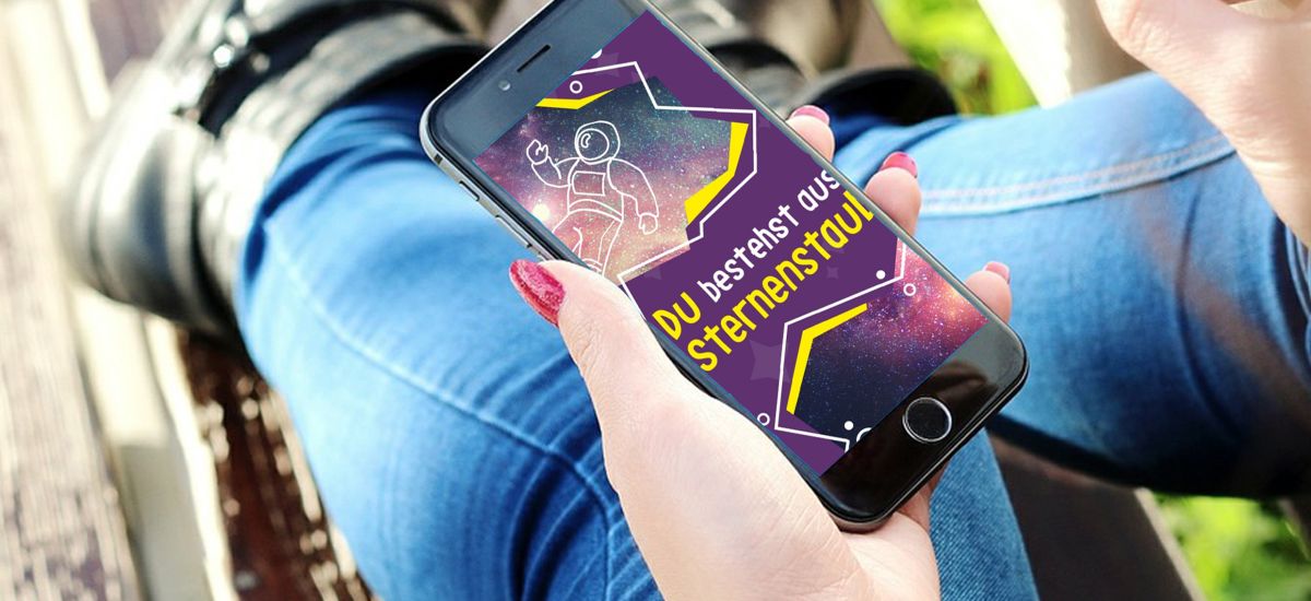 Eine weibliche Person hält ein Smartphone in der Hand. Darauf steht: Du bestehst aus Sternenstaub.