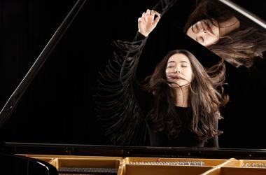 Eine junge Frau sitzt an einem Klavier.