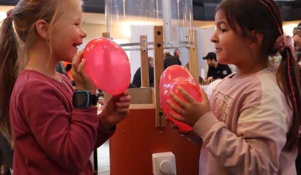 Zwei Kinder halten einen Herzluftballon in der Hand.