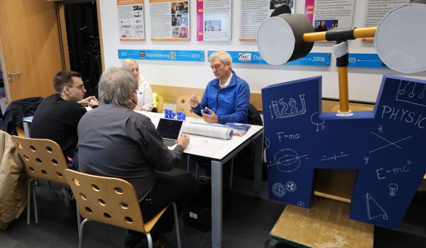 Vier Personen sitzen an einem Tisch und unterhalten sich.