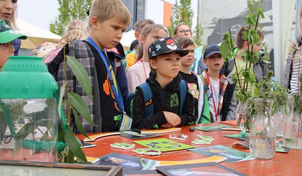 Kinder machen Experimente an einem Stand.