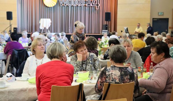 Frauen sitzen an gedeckten Tischen.