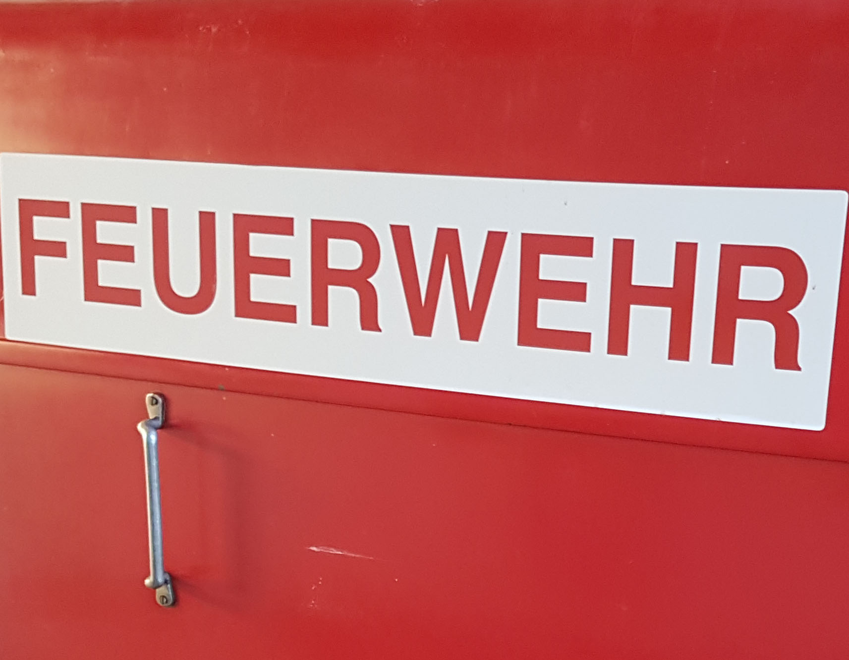 Rote Metalltür mit der Aufschrift Feuerwehr.