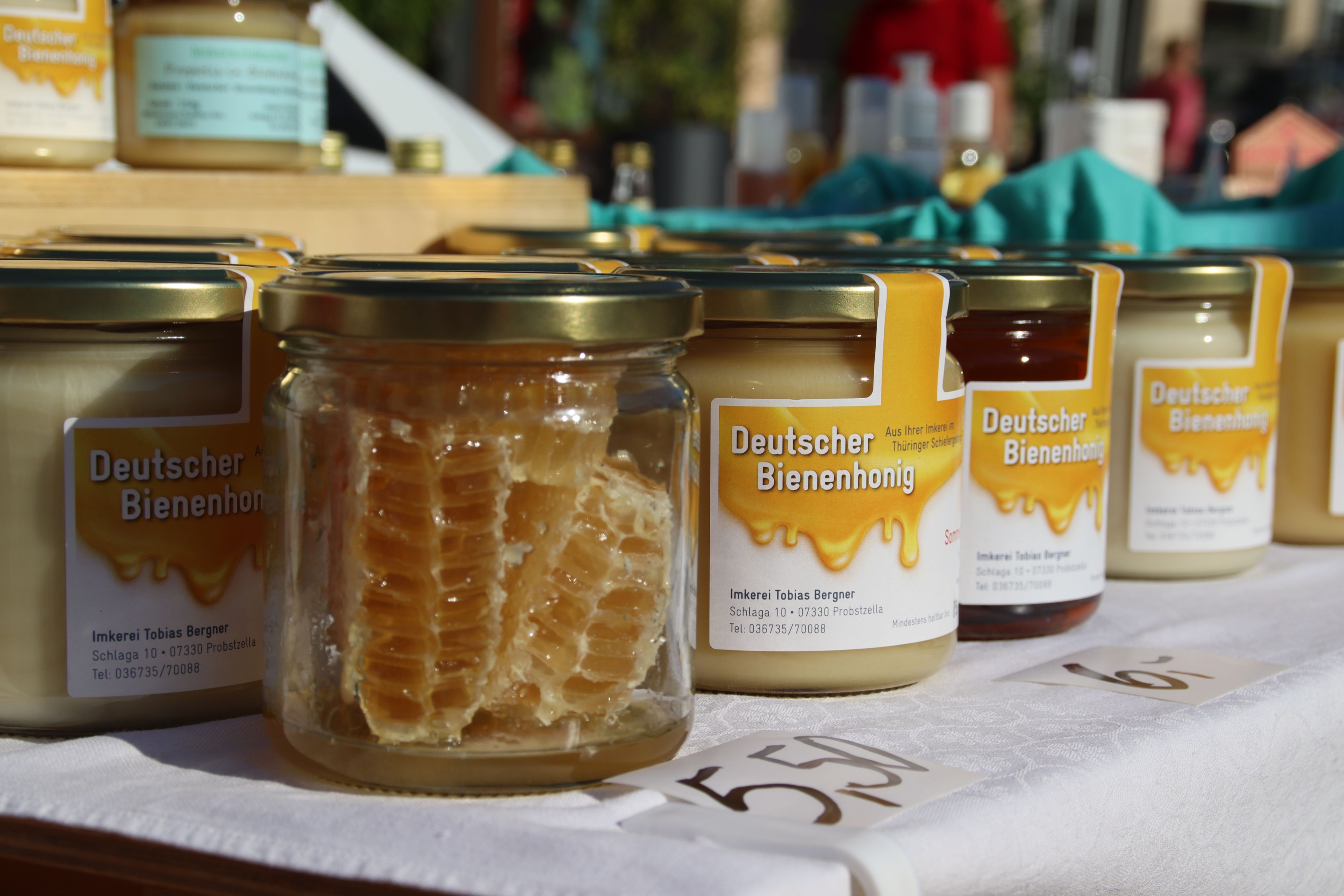 Auf einem Tisch stehen Gläser mit Honig. Auf dem Etikett steht die Aufschrift: Deutscher Bienenhonig.
