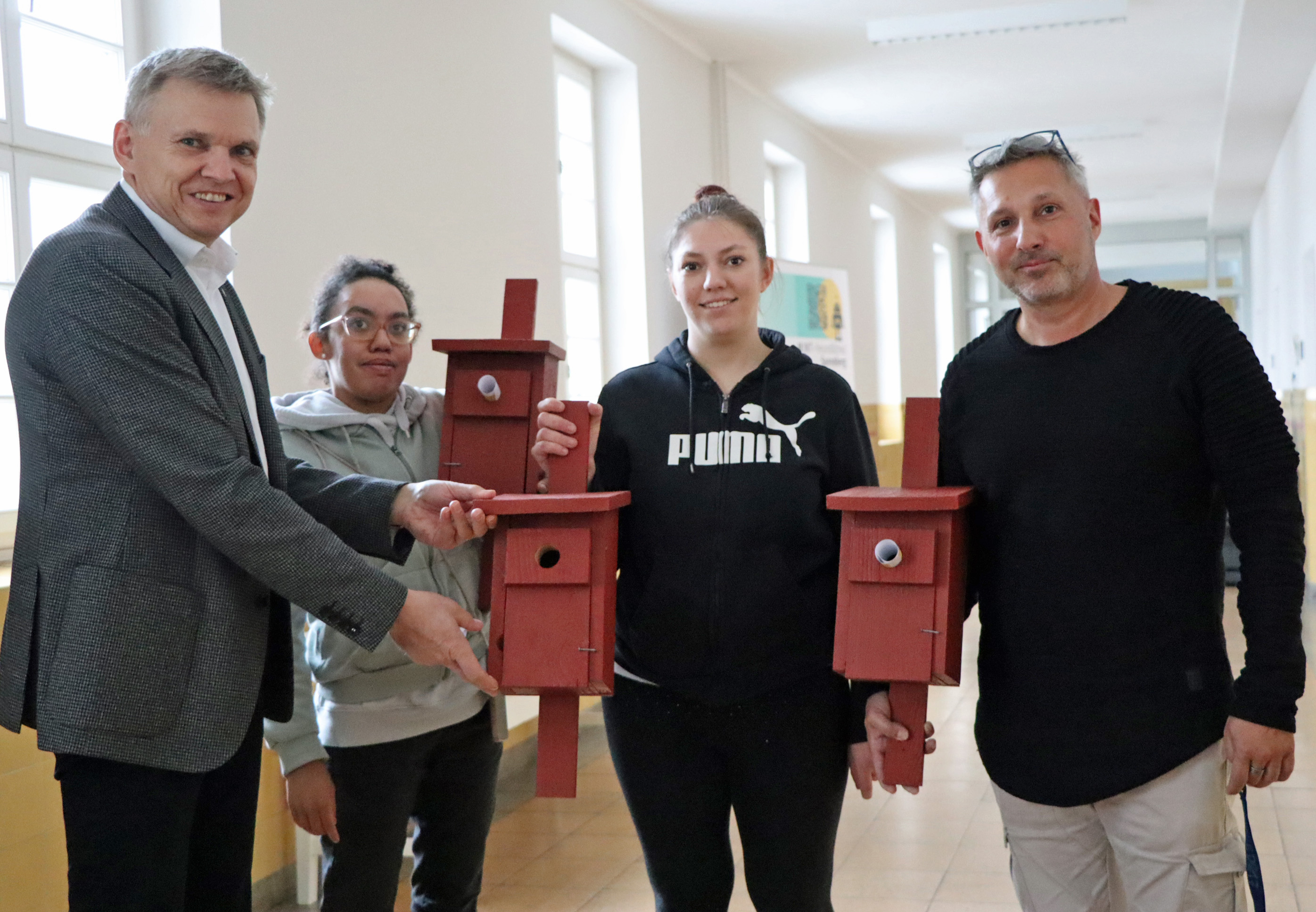 Zwei Männer und zwei Frauen zeigen die von der Werkstatt für angepasste Arbeit angefertigte Nistkästen.