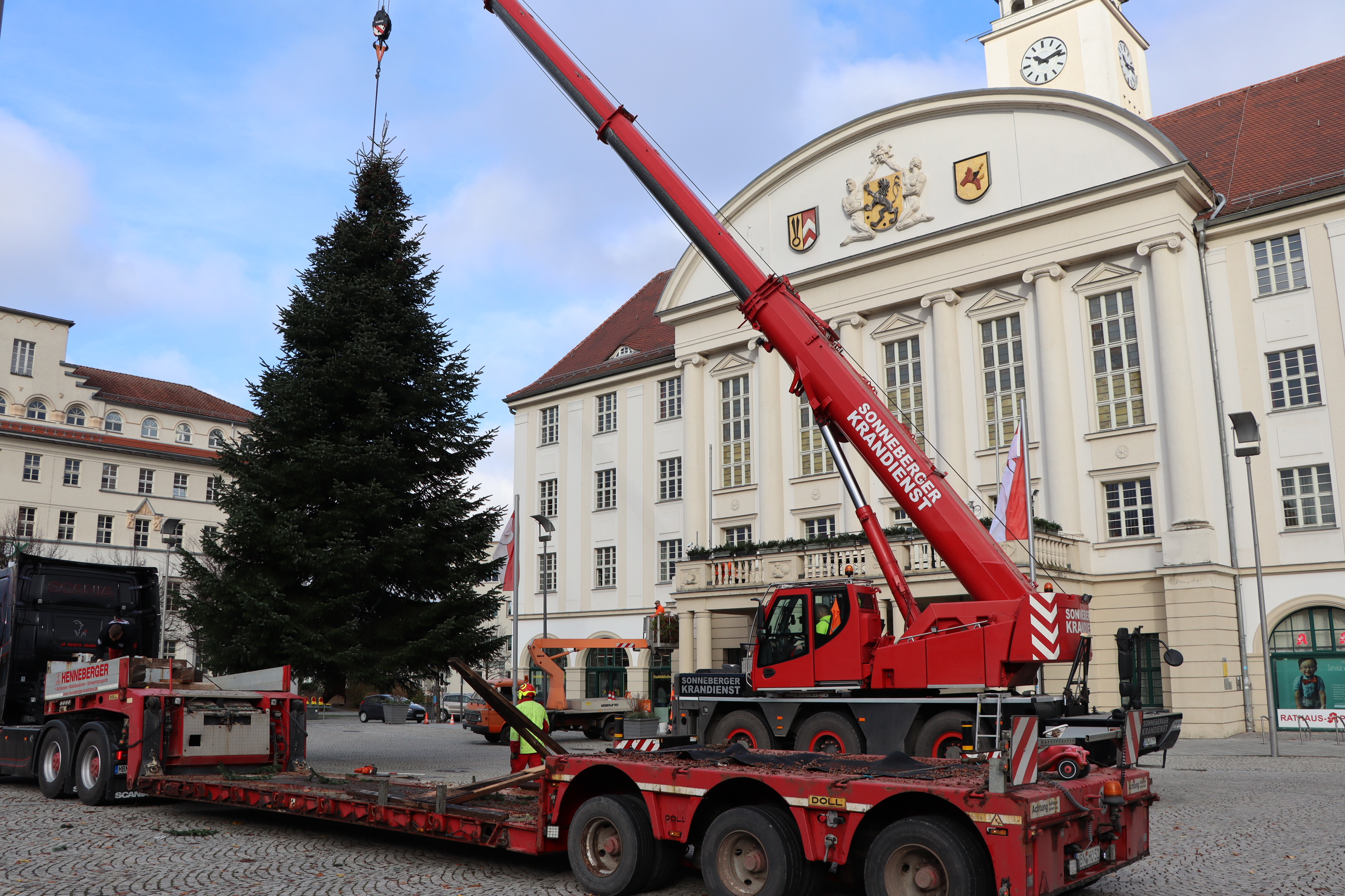 Ein Weihnachtsbaum an einem Kranhaken vor dem Rathaus.