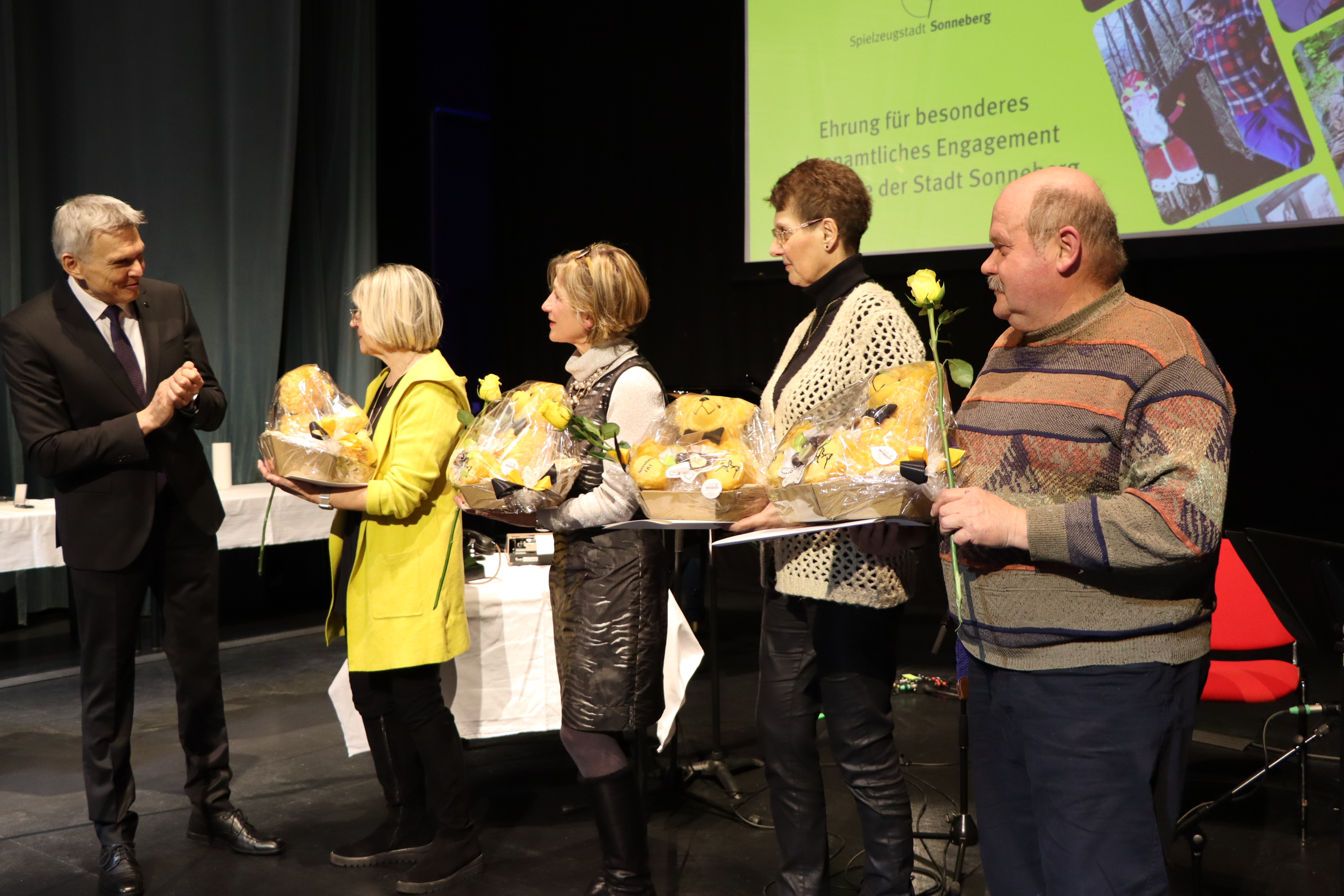 Männer und Frauen auf einer Bühne mit Geschenken.