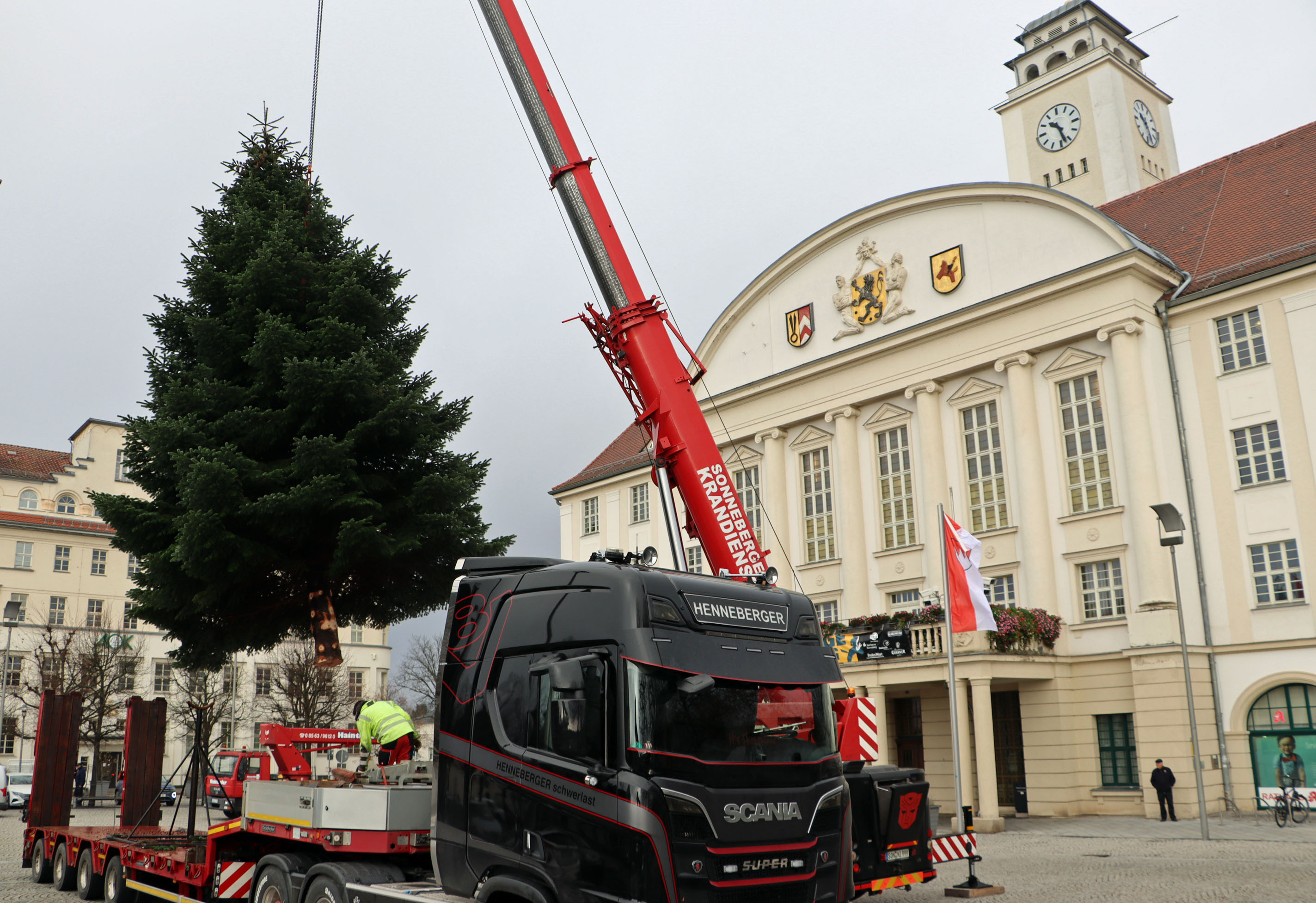 Ein Kranausleger hebt einen Weihnachtsbaum in die Mitte des Platzes vor dem Sonneberger Rathaus.
