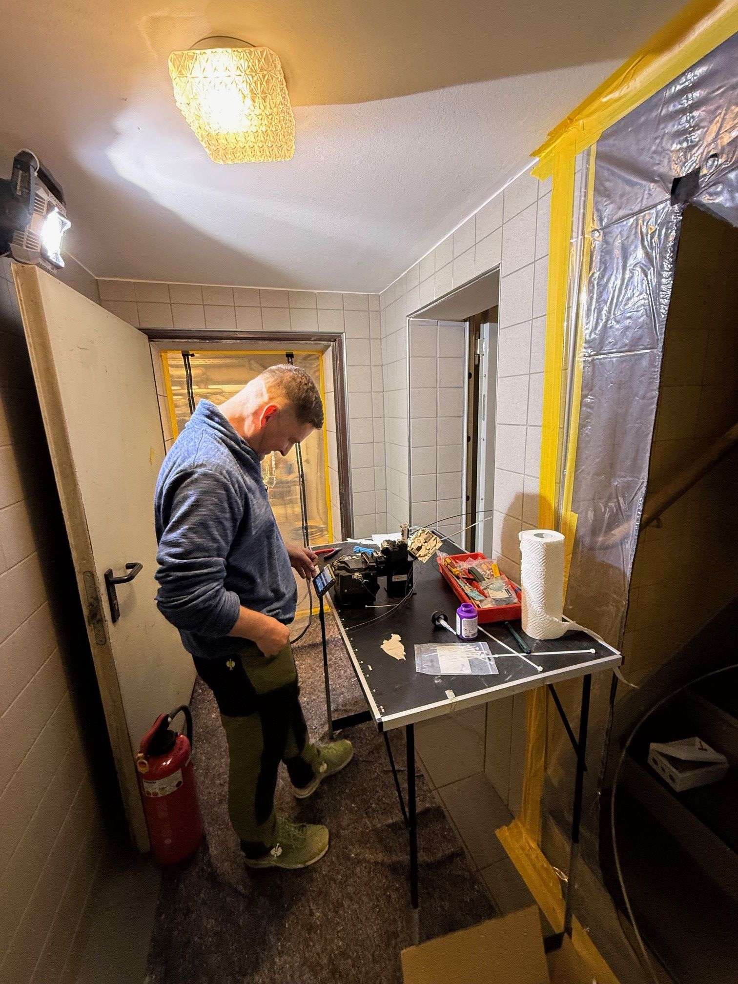 Ein Mann steht vor einem Tisch, auf dem Technik aufgebaut ist, die er repariert.