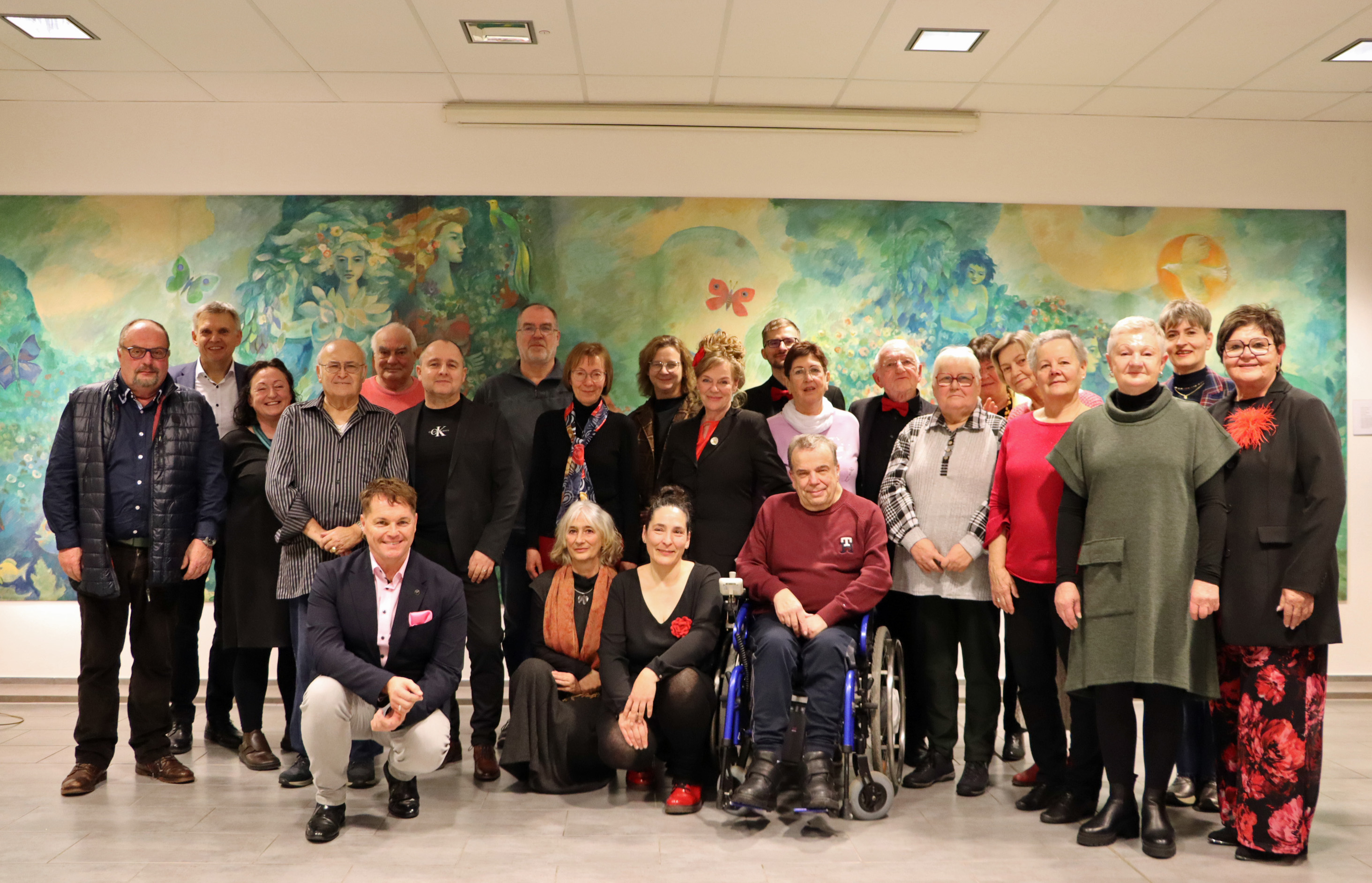 In einem Raum stehen rund 25 Männer und Frauen. Sie haben sich zu einem Gruppenfoto versammelt.