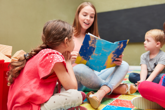 Junge Frau liest Kindern aus einem Buch vor, Foto: Robert Kneschke